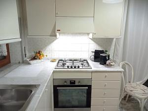 a white kitchen with a stove and a sink at Miky M House in Venosa
