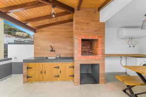 a kitchen with wooden walls and a sink and a table at Casa da Guida in Machico