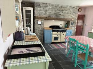 une cuisine avec des placards bleus et une table avec des chaises dans l'établissement Glenmore Cottage - Waterville, à Waterville