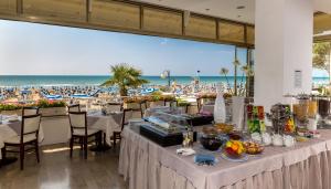 a restaurant with tables and a view of the beach at Hotel Rivamare in Lido di Jesolo