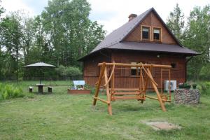 a small house with a playground in front of it at Gajówka Żłobek in Żłobek