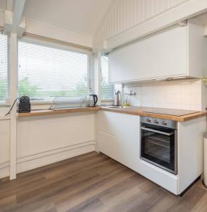 a kitchen with white cabinets and a stove top oven at Het Dijkhuysje by ZILT in Warmenhuizen
