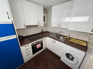 a kitchen with white cabinets and a sink and a dishwasher at Аpartamentos en primera línea de mar in Platja  d'Aro