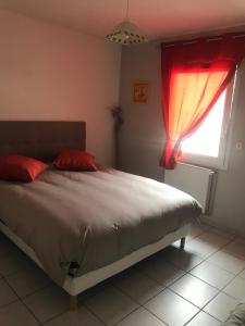a bedroom with a bed with red pillows and a window at Villa le jasmin très calme in Andrézieux-Bouthéon