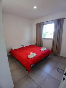 a bedroom with a red bed with two towels on it at Apartamento LH Cómodo y moderno Cerca del aeropuerto Ezeiza ex fader in Luis Guillón