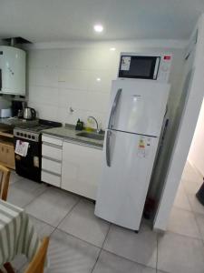a kitchen with a refrigerator with a microwave on it at Apartamento LH Cómodo y moderno Cerca del aeropuerto Ezeiza ex fader in Luis Guillón