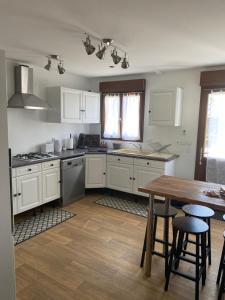a kitchen with white cabinets and a wooden table at Maison calme à la campagne in Cléré-les-Pins