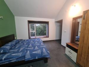 Un dormitorio con una cama con edredón azul y una ventana. en Eden Villa, en Meenangadi