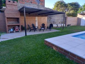 a patio with chairs and a fireplace next to a pool at Refugio de Santi in Santo Tomé
