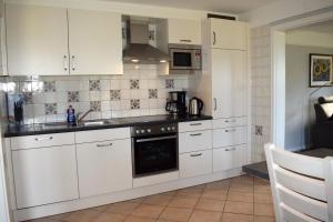 een keuken met witte kasten en een kookplaat oven bij Ferienhaus Haus Amsel Niebüll in Niebüll