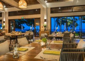 a dining room with tables and chairs and windows at Crown Retreat Quy Nhon Resort in Quy Nhon