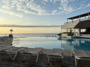 a pool with chairs and the ocean in the background at Cancun Plaza Condo Mexico in Cancún