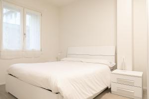 a white bedroom with a white bed and a window at Ca Borsa III - Suite nel cuore di Treviso in Treviso