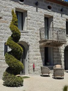a building with two benches and a tree at Hôtel confidentiel Le Grecale in Pianottoli-Caldarello