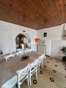 a dining room with a table and white chairs at La CONSTELLATION in LʼÉpine