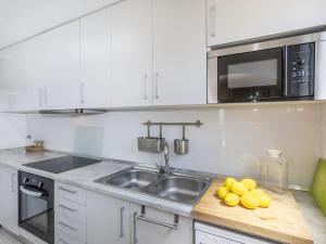 a kitchen with a sink and a microwave and some lemons at Apartment Cala Salionc by Interhome in Cañet de Mar