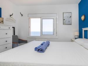 a white bedroom with a large white bed with blue walls at Apartment Cala Salionc by Interhome in Cañet de Mar