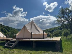 Una gran carpa blanca colocada sobre una plataforma de madera en Glamping - Casuta de pe Fiad, en Romuli