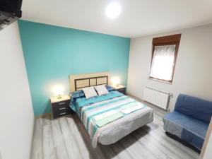 a bedroom with a bed and a blue wall at La Casina San Román de la Vega in San Justo de la Vega +3 photos