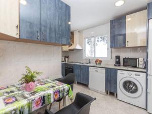 a kitchen with blue cabinets and a table and a washing machine at Holiday Home Mercury by Interhome in Lloret de Mar
