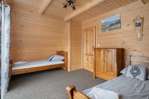 a bedroom with two beds in a log cabin at Domek góralski Toporówka - Premium in Murzasichle