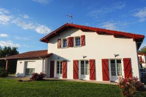 a white house with red doors and a yard at Errobi Alde in Cambo-les-Bains
