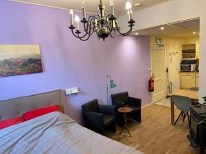 a bedroom with a bed and two chairs and a chandelier at Voorstraat 30 Studio in Colijnsplaat