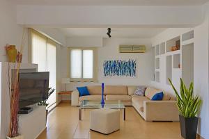 a living room with a couch and a tv at Julipapas Gardens in Paphos City