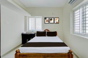 una camera da letto con un letto e due finestre di Hotel O Eswar Guest House Padur a Chennai