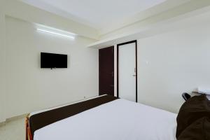a bedroom with a bed and a tv on the wall at Hotel O Eswar Guest House Padur in Chennai