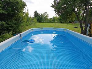 a blue swimming pool with a reflection in the water at Gólyaház in Réde
