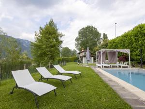 a group of lawn chairs next to a swimming pool at Villa La Casetta sul Lago by Interhome in Clusane sul Lago +70 photos