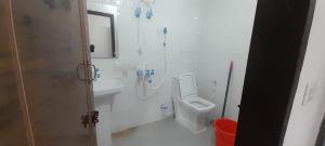 a white bathroom with a toilet and a sink at Shree Sai Stay in Gurgaon +1 photo