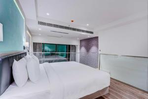 a bedroom with a large white bed and a window at Luxurious Residences by Sunday at M3M Broadway Sec 71 in Gurgaon