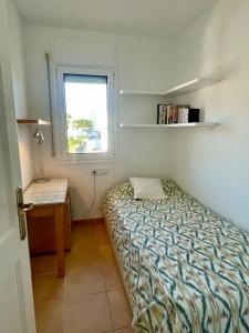 a small bedroom with a bed and a window at Confort al cor de Calella in Palafrugell
