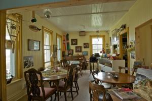 comedor con mesas y sillas y cocina en Auberge du Café chez Sam en Baie-Sainte-Catherine