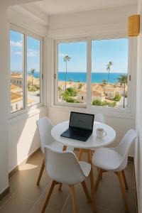 Habitación blanca con mesa, sillas y ordenador portátil en La Cala de Mijas apartment, Sea View, 200m from the beach, close to town, en La Cala de Mijas
