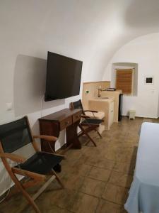 a room with chairs and a desk and a television at Kamara Nest - More than a stay in Aroniadika