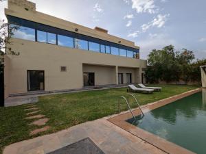 a house with a swimming pool in front of it at Villa moulay abdella in Marrakesh