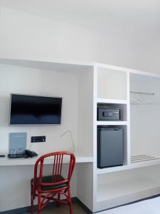 a red chair sitting next to a desk with a tv at Hotel Paradiso Portovenere in Portovenere