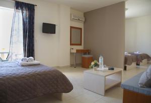 a bedroom with a bed and a couch and a tv at Hotel Sea Breeze in Sitia