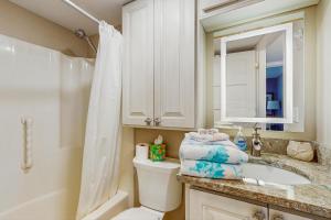 a bathroom with a toilet and a sink and a mirror at Tide & Teal in Fort Myers Beach +12 photos