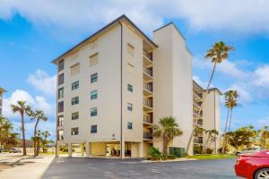 a white building with palm trees in front of it at Tide & Teal in Fort Myers Beach