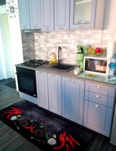 a kitchen with white cabinets and a stove with peppers on the floor at Apartament spațios 70mp cu 2 camere in Mamaia