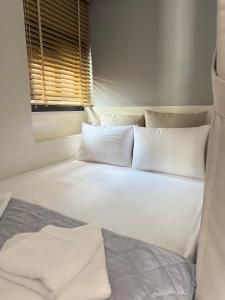a bedroom with two beds with white pillows and a window at G&S Dionisiou Apartment in Paralia Dionysiou