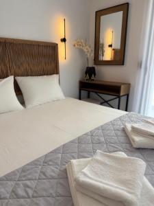 a bedroom with a large white bed with a mirror at G&S Dionisiou Apartment in Paralia Dionysiou