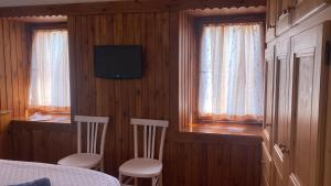 a bedroom with a bed and two chairs and a television at La Casa di Theo in Padola