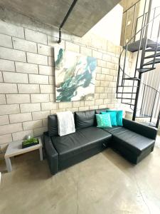 Un sofá de cuero negro sentado frente a una pared de ladrillos. en Modern 2 Bdrm w/Parking in the Heart of Hillcrest, en San Diego