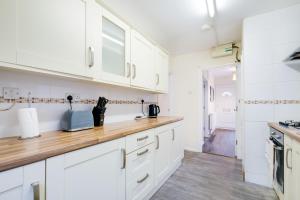 a kitchen with white cabinets and a wooden counter top at 4 Bedroom High Wycombe Home With Free Parking Free WiFi Private Garden - Great Transport Links! in Buckinghamshire