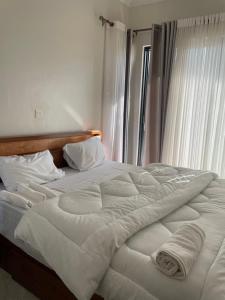 a large white bed in a room with a window at Cozy Home-Rusororo-near airport in Kigali